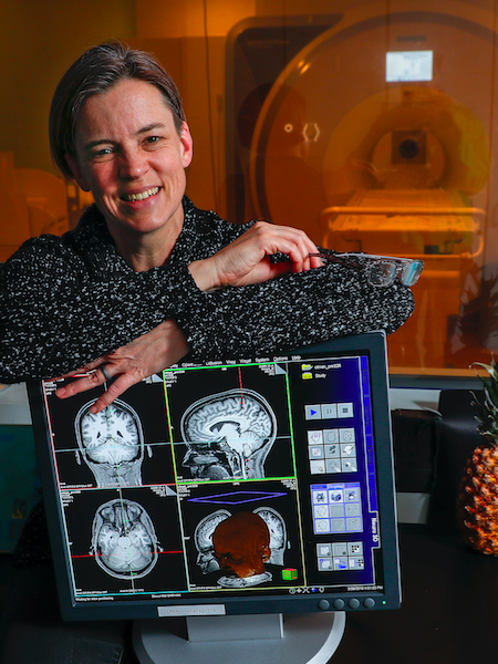 Cheryl Olman leaning on a computer screen showing brain scans
