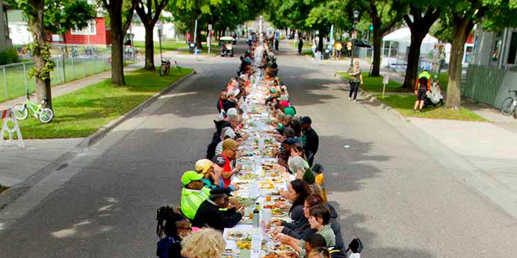 Photo of Frogtown Community Meal: long dinner table with seated guests down Victoria St in St Paul