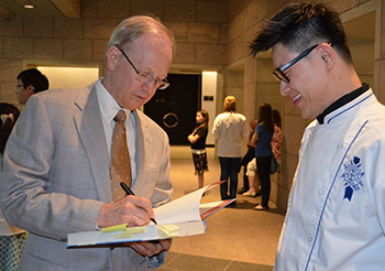 Image of alum and donor Wayne Gisslen signing one of his cookbooks