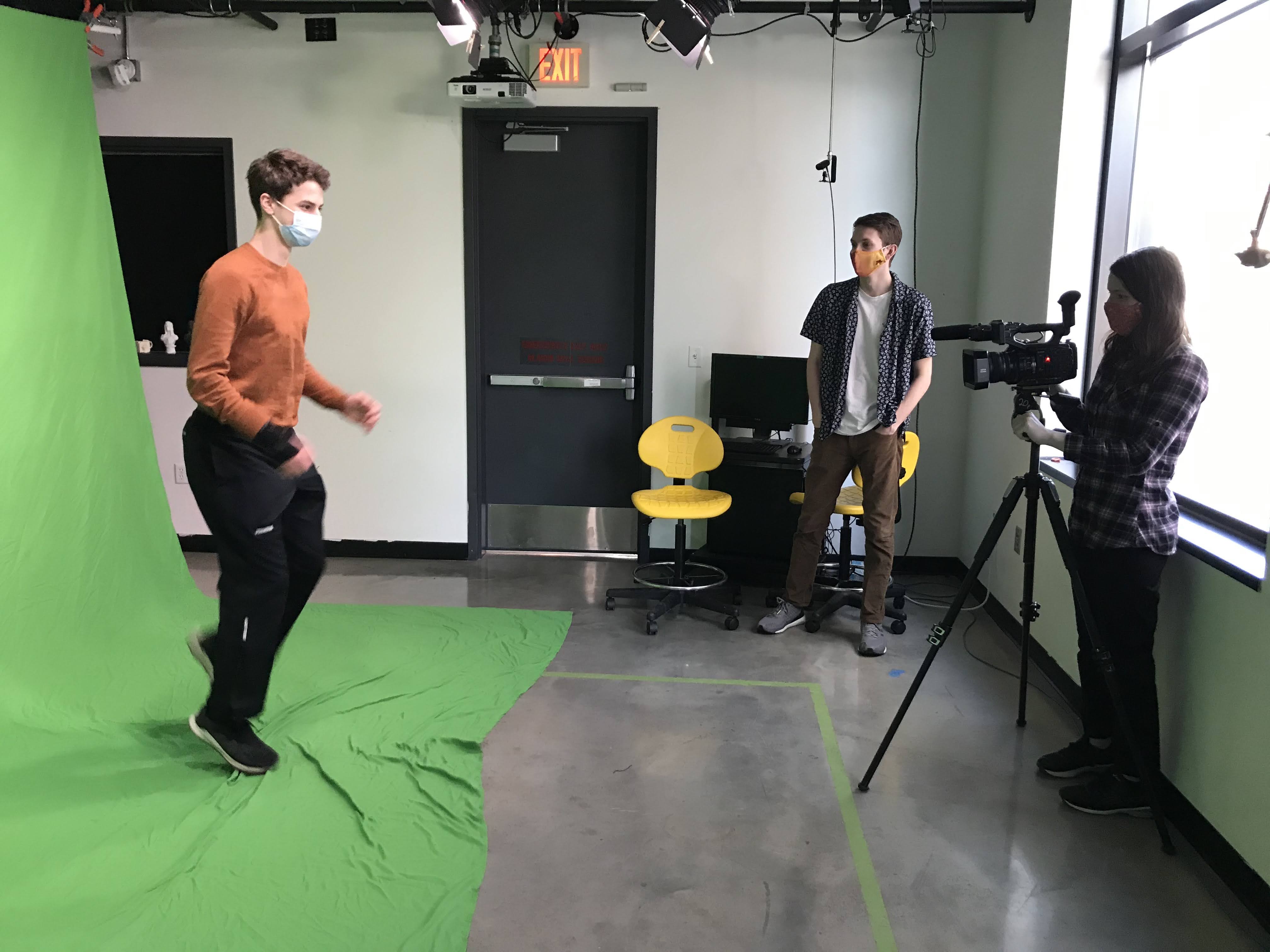 students filming another student pretending to run against a green screen