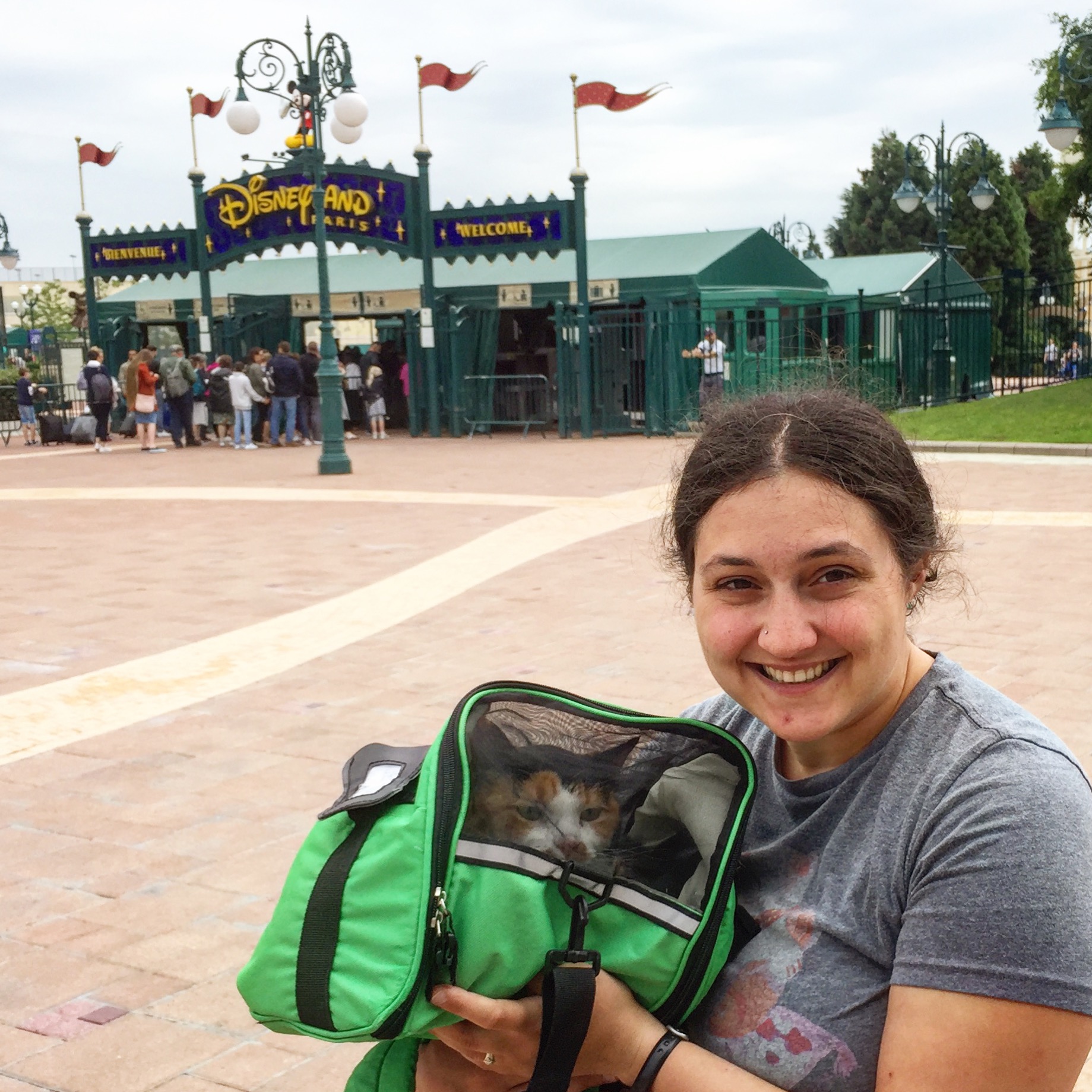 Woman holding cat in carrier in front of Disneyland in France