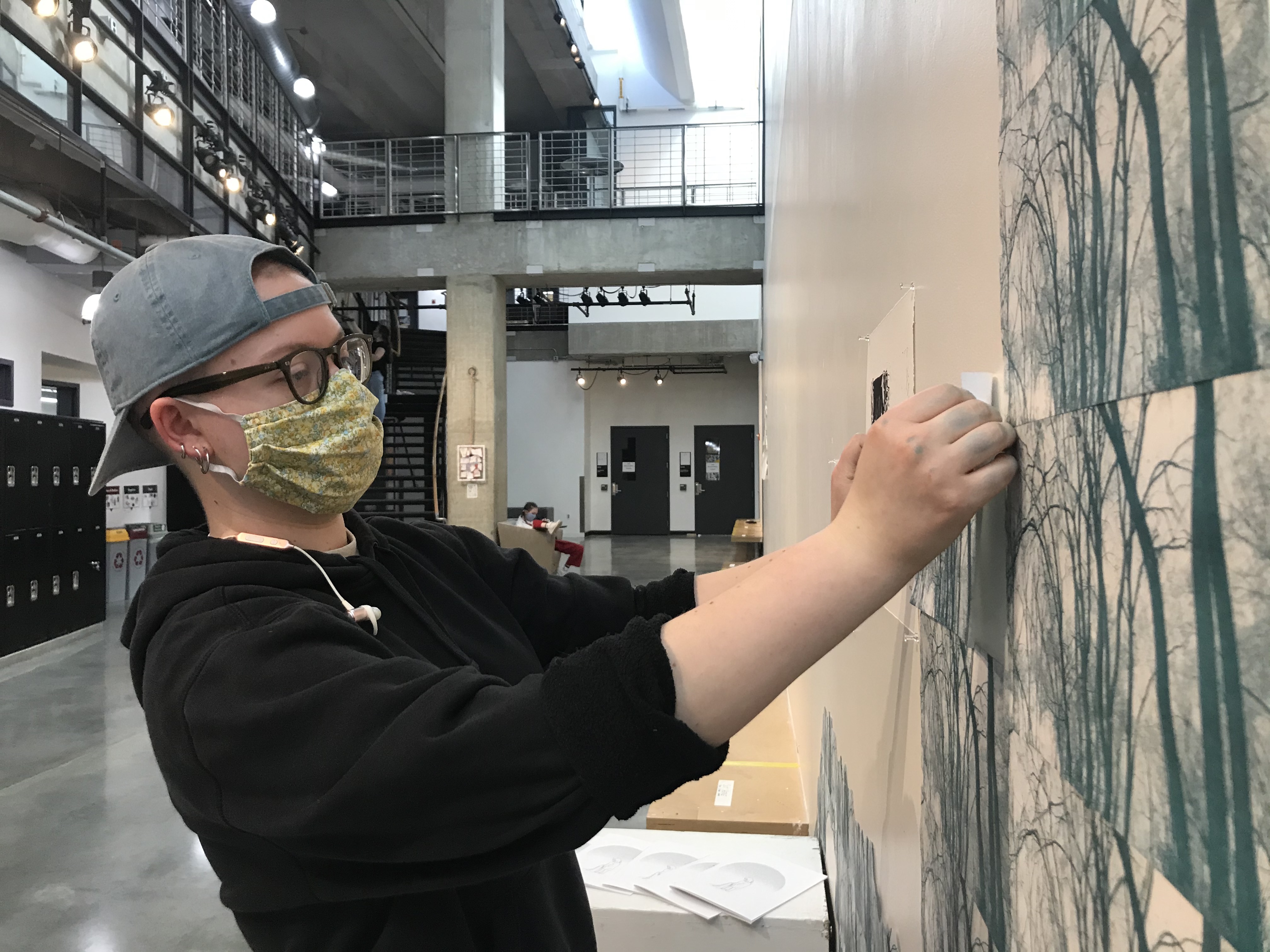 Student pins multiple tree prints to the gallery wall