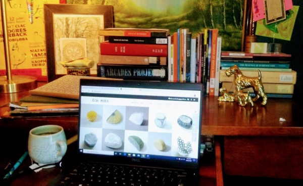 Photo of Prof Kathryn Nuernberger's desk, with painting of forest glade above and golden dog curios on shelf