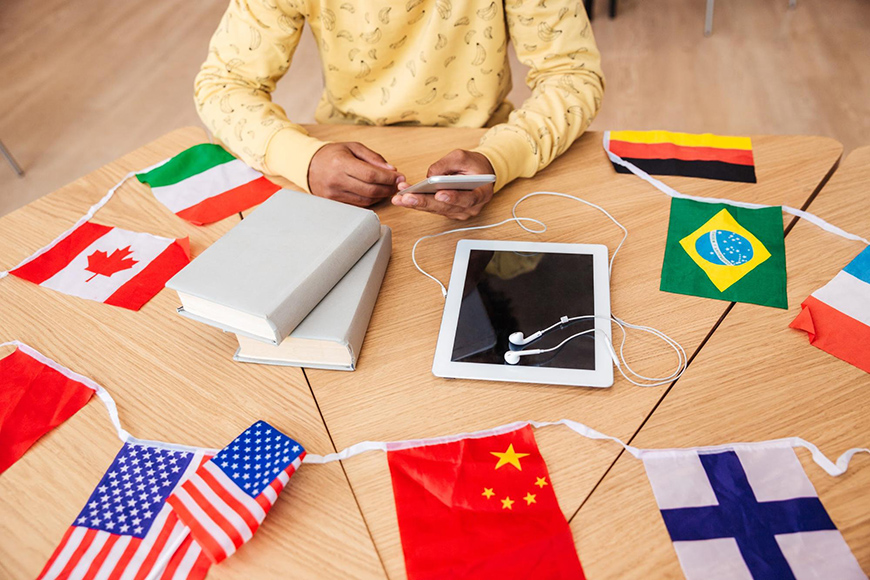 person sitting at table with tablet and books surrounded by flags