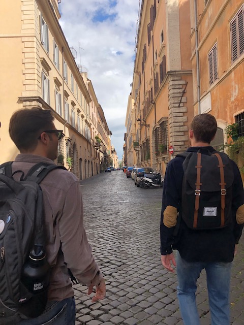 picture taken behind two students looking down a Roman street