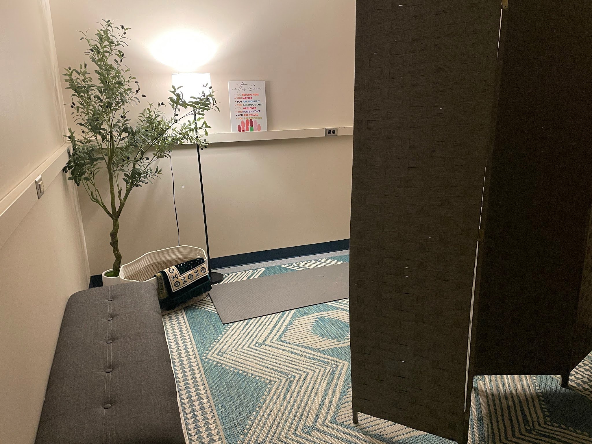 Wellness room with a folding screen, bench, carpet and fake tree