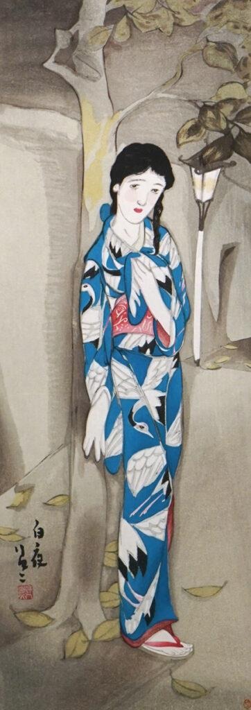 Girl in blue printed fabric leaning on a tree